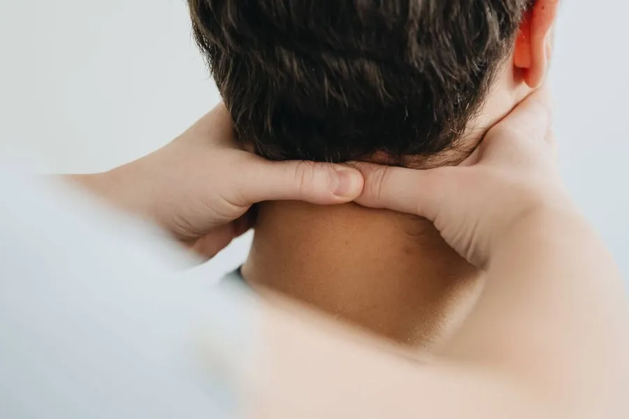 Manos de un fisioterapeuta tratando la nuca y el cuello de un paciente
