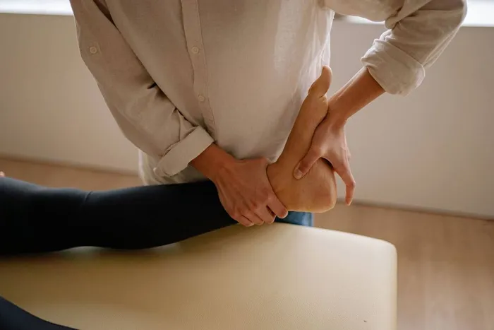Manos tratando el pie de una persona tumbada en camilla